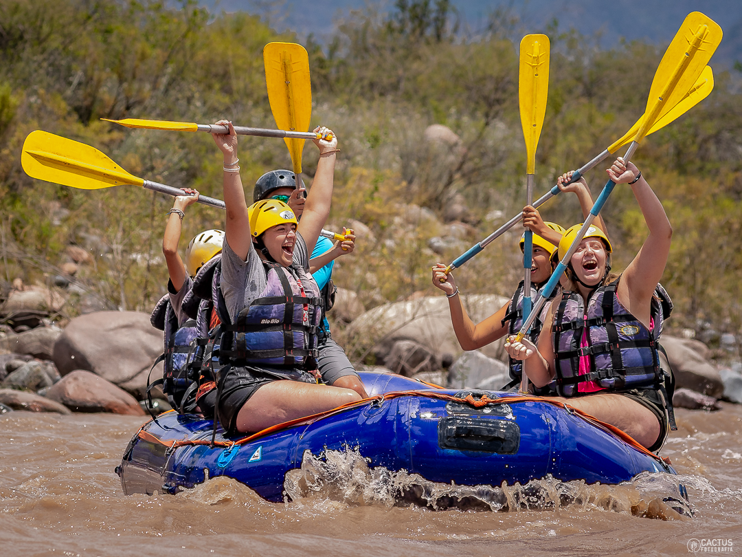 Personas celebrando con los remos levantados durante el rafting